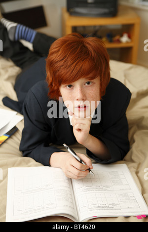 Schoolboy doing his homework in the bedroom. Stock Photo