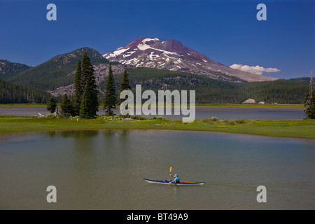 SPARKS LAKE, OREGON, USA - Man paddles kayak, South Sister, a volcano in the Cascades mountains of Central Oregon. Stock Photo