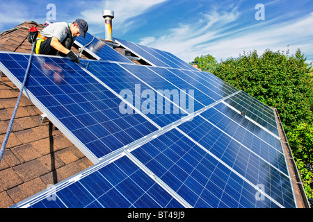 Man installing alternative energy photovoltaic solar panels on roof Stock Photo
