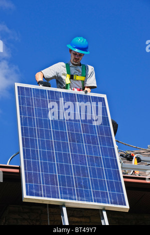 Man installing alternative energy photovoltaic solar panels on roof Stock Photo