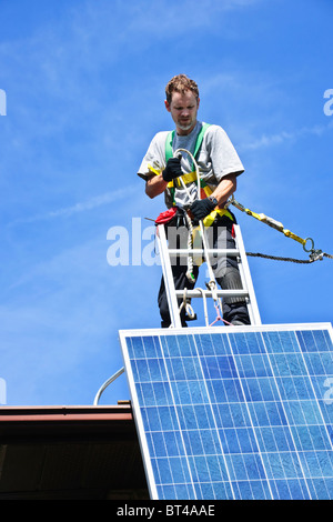 Man installing alternative energy photovoltaic solar panels on roof Stock Photo