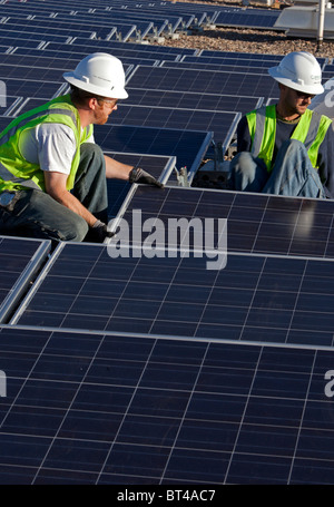 Denver, Colorado - Workers install solar photovoltaic panels on the roof of Harrington Elementary School. Stock Photo