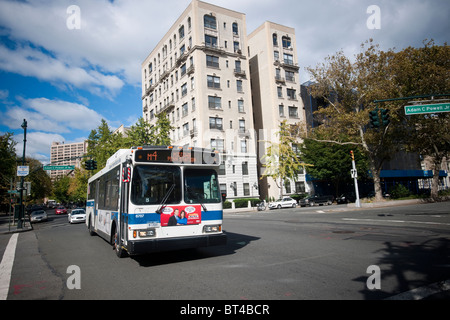 A NYC Transit bus travels through an intersection on Central Park North in Harlem in New York Stock Photo