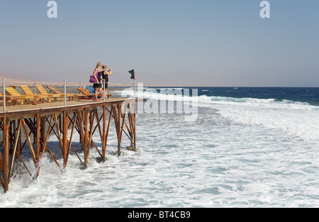 Two women on bridge looking big waves - Red Sea, Egypt Stock Photo