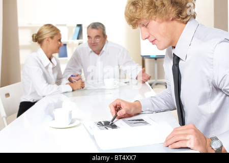 Portrait of confident businessman thinking over business plan with communicating partners at background Stock Photo