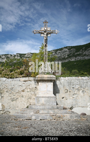 A large metal crucifix on stone plinth in a rural mountain village cemetery in France. Stock Photo