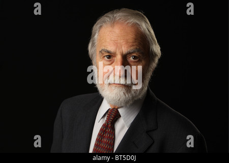 Portrait of bearded and grey haired senior businessman in suit and tie, studio shot, black background, October 16, 2010 Stock Photo