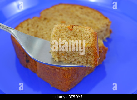Carrot cake on a blue plate with small piece on fork Stock Photo