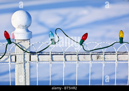 String of colored Christmas lights on a white fence, Gimli, Manitoba, Canada. Stock Photo