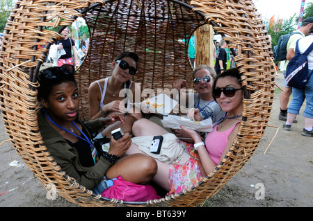 woven wicker basket chair globe hanging round circular girl girls lunch eating resting relaxed sun glasses sat seated smile happ Stock Photo