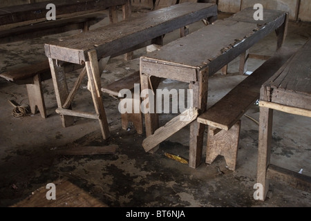 Old broken wooden tables and benches in poor condition serve students at a primary school in communist Laos. Stock Photo