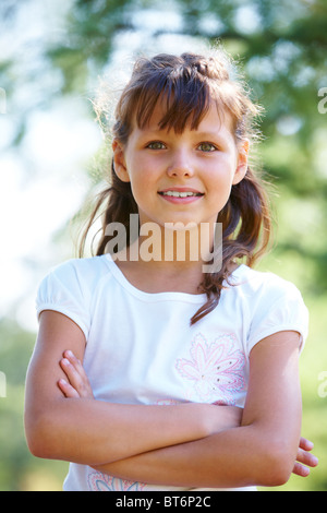 Portrait of happy girl crossing arms while posing outside Stock Photo