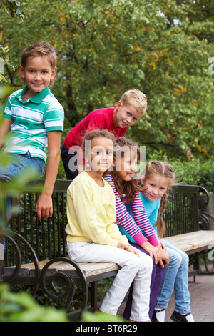 Portrait of happy friends resting on bench in park