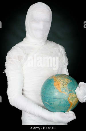 Man in costume mummy and terrestrial globe on black Stock Photo