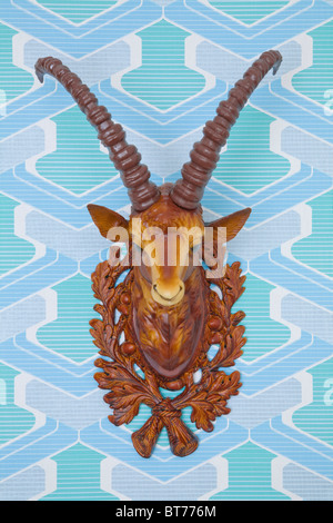 Plastic head of an ibex mounted on kitschy wallpaper from the 1960s or 1970s, frontal view Stock Photo