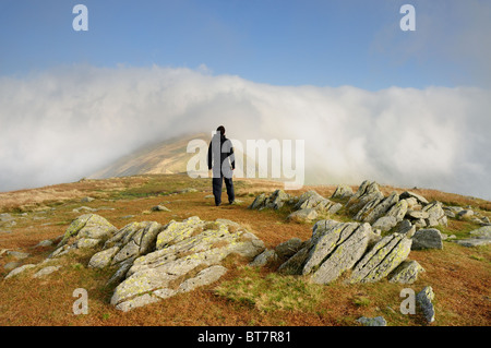 Walker on Great Rigg looking towards the cloud shrouded summit of Fairfield in the English Lake Distrct Stock Photo