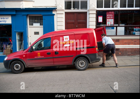 A postman loading a sack of mail into his van UK Stock Photo