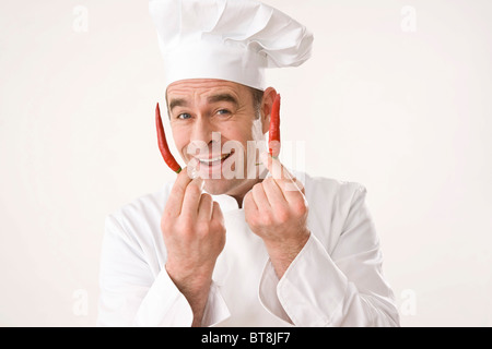 Cook holding two chili peppers, smiling Stock Photo