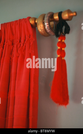 Close-up of red velvet curtain and tassel on wooden curtain-pole Stock Photo