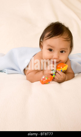cute kid lying down on his tummy on blanket with stuck out tongue Stock Photo