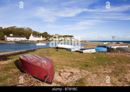 Upturned boats with view to The Ship Inn and village across small harbour in Red Wharf Bay, Isle of Anglesey, North Wales, UK. Stock Photo