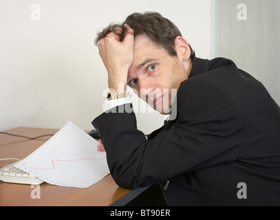 Sorrowful man at the office, on a workplace with graph Stock Photo