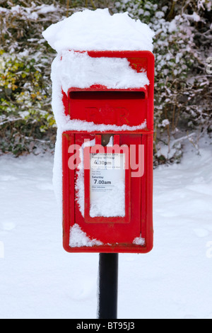A traditional red English postbox at winter time covered in snow. Stock Photo