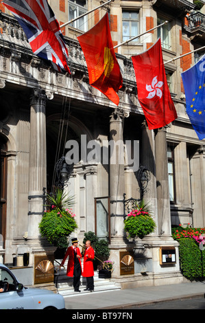 Flags above two doormen at the entrance to the luxury five star Mandarin Oriental Hyde Park Hotel in London Knightsbridge England UK taxi waiting Stock Photo