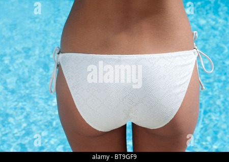 A woman in a white bikini by a pool, rear view Stock Photo