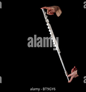 A complete silver flute in womans hands, isolated on black background. Stock Photo
