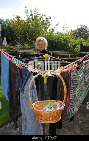 Middle aged woman hanging out her clean washing on whirl gig washing line Stock Photo