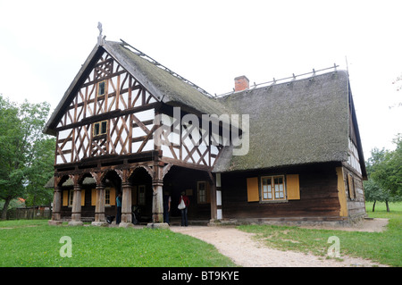 Replica of early 20th century hut with arcade extension, partly half-timbered wall and thatched roof from Masuria region, Poland Stock Photo