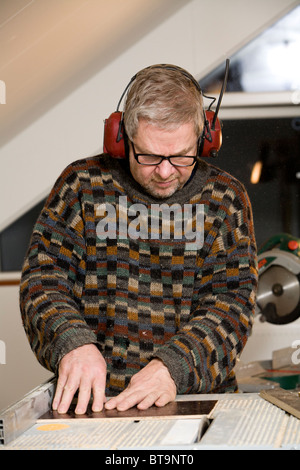 Man trimming a piece of plywood. Stock Photo