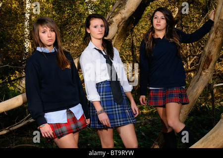 Three high school teenage girls in private school uniforms hanging out in a thick forest Toronto Stock Photo
