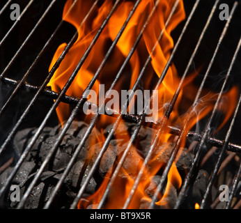 Flames in a BBQ charcoal grill after igniting the charcoal briquettes. Focus is on the grill rack and the charcoal tips. Stock Photo