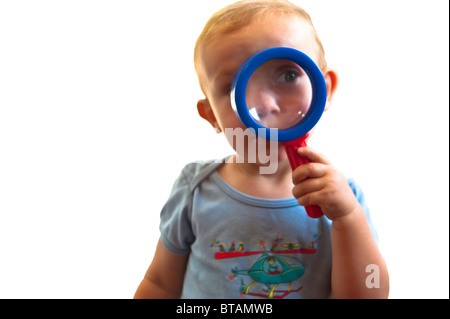 Curious little boy peering through a magnifying glass Stock Photo