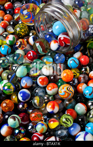 Glass jar spilling marbles Stock Photo