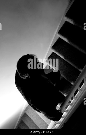 Silhouette of a man walking up a dark stairway Stock Photo