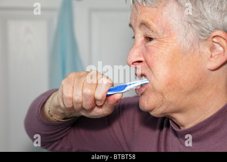 Senior woman brushing her teeth with a manual toothbrush. UK, Britain. Stock Photo