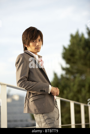 Young man leaning on railing Stock Photo