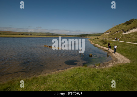 People stroll beside the winding waters of Cuckmere Haven Stock Photo