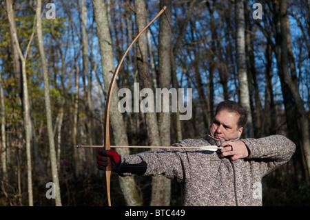 Man shooting with bow and arrow in forest, Stockholms Lan, Sweden Stock Photo