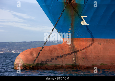 bulbous bow hull markings and anchor chain of coastal deniz dry cargo hazard a major ship at anchor in coastal waters of the uk Stock Photo
