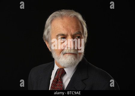 Portrait of bearded and grey haired senior businessman in suit and tie, studio shot, black background, October 16, 2010 Stock Photo