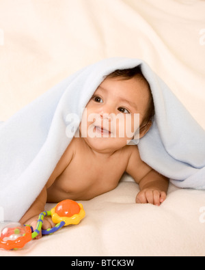 cute kid lying down on his tummy on blanket with stuck out tongue playing peek-a-boo Stock Photo
