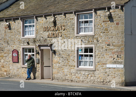 Man smoking outside the Masons Arms pub in the village of Gargrave, North Yorkshire, England UK Stock Photo