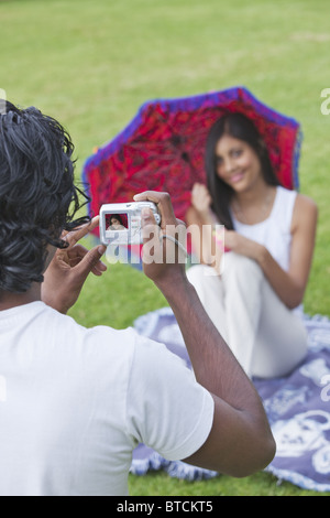 Indian man and woman using digital camera to capture memories in a park. Stock Photo