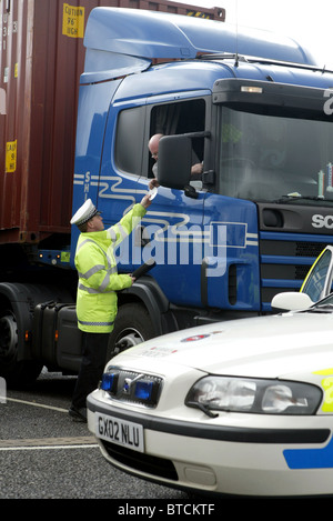 British traffic Police Officer checking on long-distance lorry drivers credentials Stock Photo