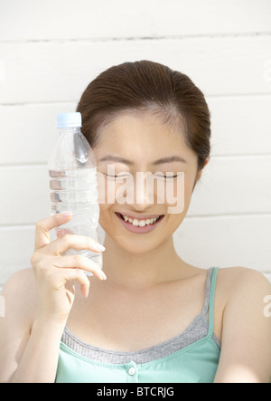 Woman putting plastic bottle on her face Stock Photo