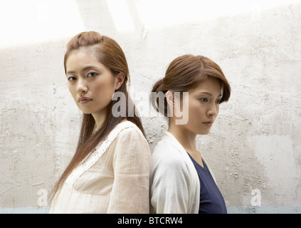 Two young women standing back to back, white background Stock Photo - Alamy
